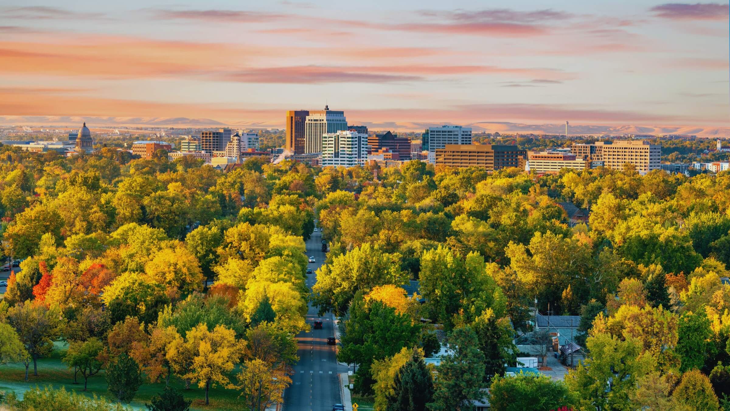 Boise skyline at sunset surrounded by autumn foliage and green trees